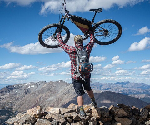 The author, Chris Reichel, heaves his trusty singlespeed above his head after reaching the top of Mount Elbert. Photo: Liz Sampey