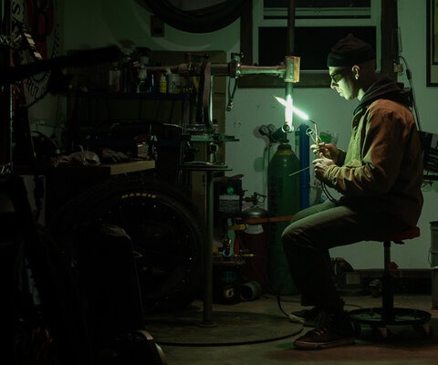 Illuminated by the glow of his welding torch, amateur framebuilder Skylar Hinkley works on his latest creation.