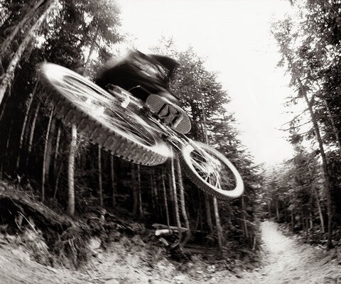 Even before it was finished, builders and riders alike knew A-Line was something special. Richie Schley gets a little taste of the now-famous trail before anyone else, while the trail crew’s Marty Gautrey uses an excavator to build even more jumps around the corner.  Photo: Blake Jorgenson